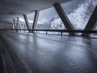 a motorcycle is going down the highway in the snow, under a bridge that goes above it