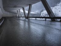 a motorcycle is going down the highway in the snow, under a bridge that goes above it