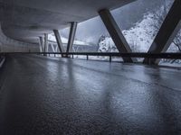 a motorcycle is going down the highway in the snow, under a bridge that goes above it