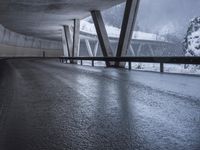 a motorcycle is going down the highway in the snow, under a bridge that goes above it