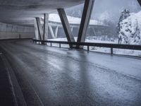 a motorcycle is going down the highway in the snow, under a bridge that goes above it