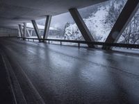 a motorcycle is going down the highway in the snow, under a bridge that goes above it