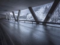 a motorcycle is going down the highway in the snow, under a bridge that goes above it