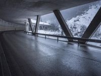 a motorcycle is going down the highway in the snow, under a bridge that goes above it