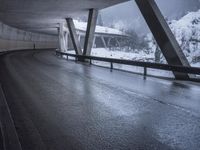 a motorcycle is going down the highway in the snow, under a bridge that goes above it