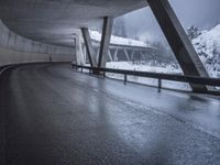 a motorcycle is going down the highway in the snow, under a bridge that goes above it