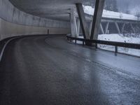 a motorcycle is going down the highway in the snow, under a bridge that goes above it