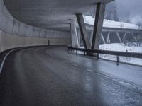 a motorcycle is going down the highway in the snow, under a bridge that goes above it