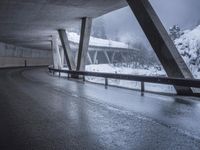 a motorcycle is going down the highway in the snow, under a bridge that goes above it