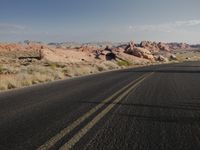 a lone motorcycle drives down a mountain road in the desert or in the middle of the desert