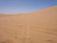 a motorcycle is in the desert looking over its body at the other side of the dune