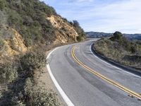 a motorcycle is parked by the side of a road in a mountainside setting with trees