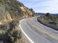 a motorcycle is parked by the side of a road in a mountainside setting with trees