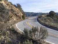 a motorcycle is parked by the side of a road in a mountainside setting with trees