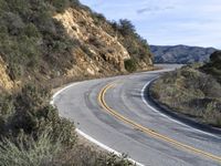 a motorcycle is parked by the side of a road in a mountainside setting with trees