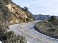 a motorcycle is parked by the side of a road in a mountainside setting with trees