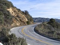 a motorcycle is parked by the side of a road in a mountainside setting with trees