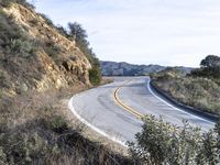 a motorcycle is parked by the side of a road in a mountainside setting with trees