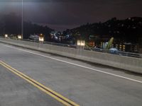 the back end of a motorcycle traveling over an empty highway at night time, near a large mountain