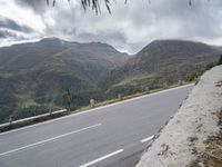 a motorcycle is traveling down the side of a road near the mountains and hills of the country