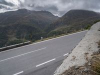 a motorcycle is traveling down the side of a road near the mountains and hills of the country