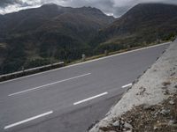 a motorcycle is traveling down the side of a road near the mountains and hills of the country