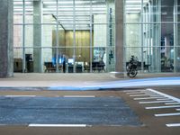 a motorcycle parked in front of a building with glass doors on it and an empty parking space