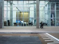 a motorcycle parked in front of a building with glass doors on it and an empty parking space