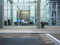 a motorcycle parked in front of a building with glass doors on it and an empty parking space