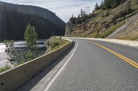 two motorcycles driving along the side of the road in front of some mountains and water