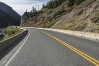 two motorcycles driving along the side of the road in front of some mountains and water