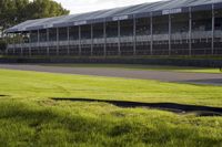 a group of motorcycles sitting in the grass near a race track with an empty grass area