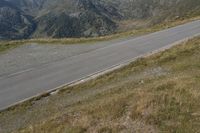 two motorcycles are traveling down the road beside some mountain peaks in a mountainous area in europe