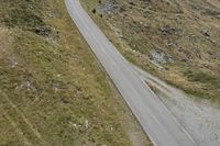 two motorcycles are traveling down the road beside some mountain peaks in a mountainous area in europe