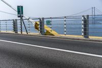 a motorcyclist on the road by the water and bridge, with the road to the left