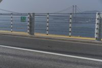 a motorcyclist on the road by the water and bridge, with the road to the left