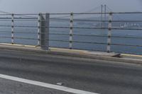 a motorcyclist on the road by the water and bridge, with the road to the left