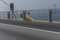 a motorcyclist on the road by the water and bridge, with the road to the left