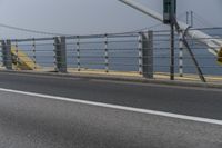 a motorcyclist on the road by the water and bridge, with the road to the left