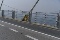 a motorcyclist on the road by the water and bridge, with the road to the left