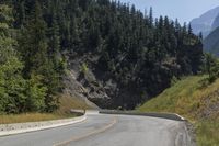 a man riding on a motorcycle down the middle of the road next to a mountain