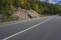 there is a man riding his bike down the road through the mountains of canada and on the motorcycle is a motorcyclist