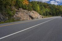 there is a man riding his bike down the road through the mountains of canada and on the motorcycle is a motorcyclist