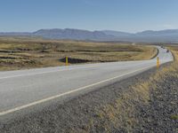 motorcyclist riding down a deserted highway in an arid landscape with mountains and hills in the background