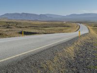 motorcyclist riding down a deserted highway in an arid landscape with mountains and hills in the background