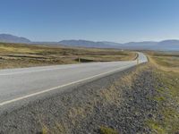 motorcyclist riding down a deserted highway in an arid landscape with mountains and hills in the background