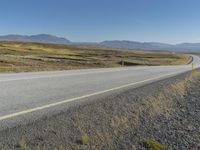 motorcyclist riding down a deserted highway in an arid landscape with mountains and hills in the background