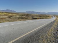 motorcyclist riding down a deserted highway in an arid landscape with mountains and hills in the background