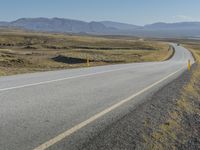 motorcyclist riding down a deserted highway in an arid landscape with mountains and hills in the background