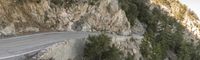 a motorcyclist riding up the side of the road between a canyon of mountains